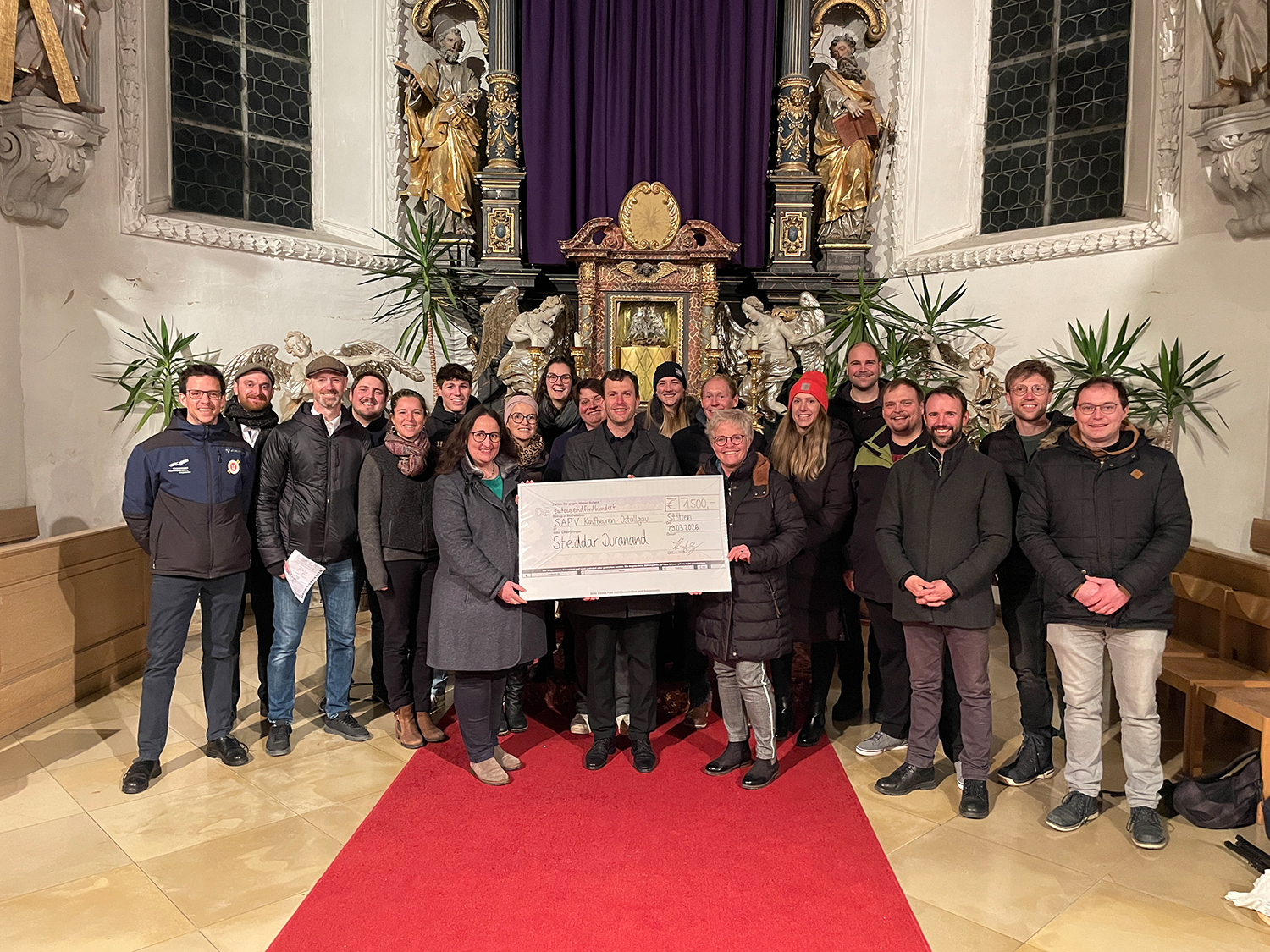 Gruppenfoto der MusikerInnen mit dem Spendenscheck